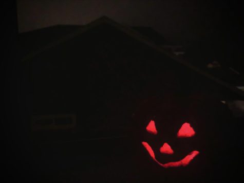 A red Jack O Lantern sits against a foggy Halloween nightscape